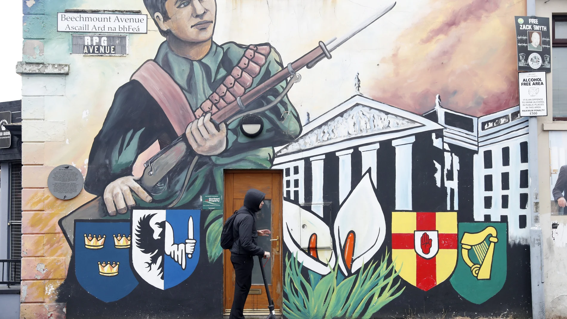 Un joven pasa con un patín junto a un mural republicano en Belfast