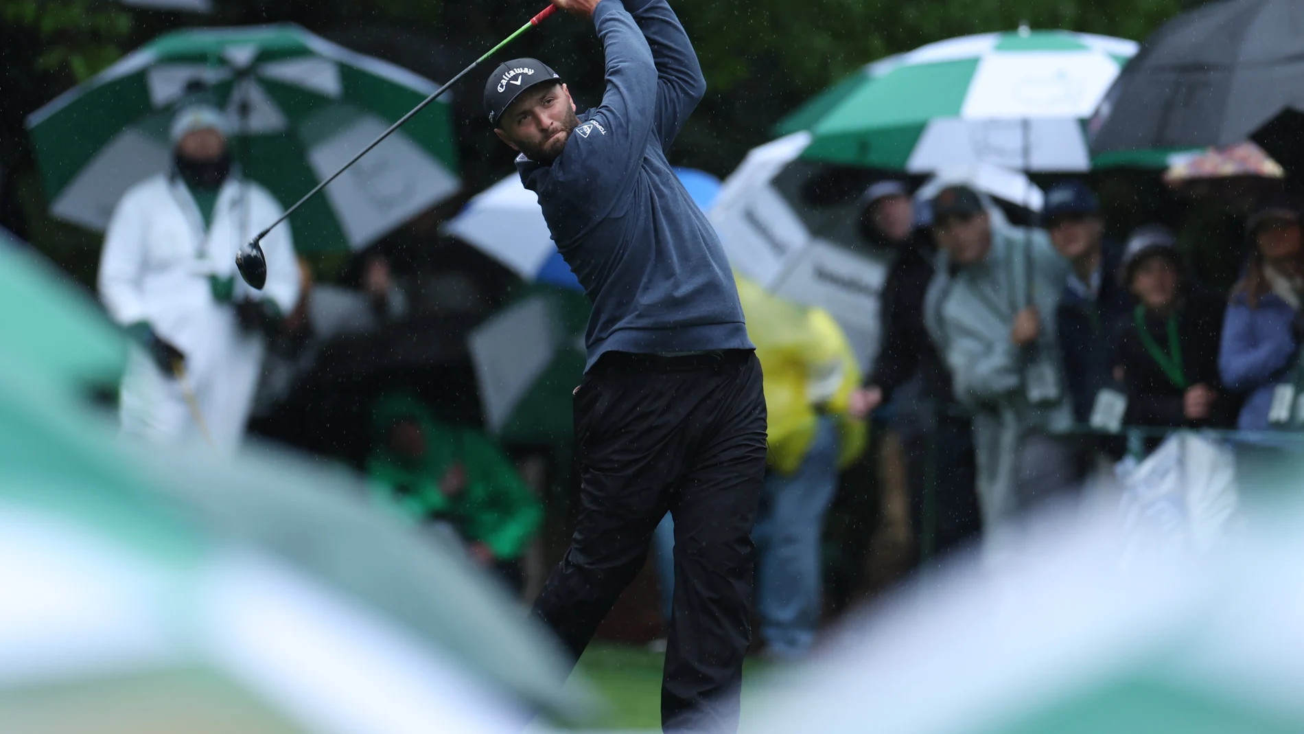 Jon Rahm golpea una bola bajo la lluvia en Augusta