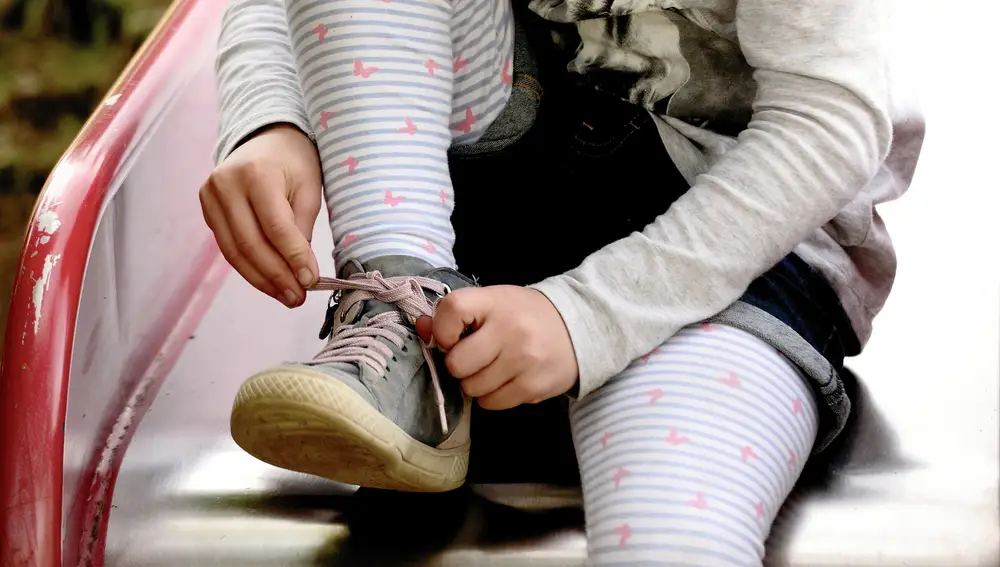 En la imagen, una niña se ata los cordones