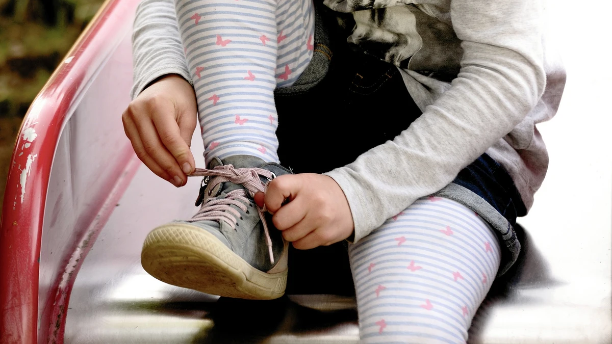 En la imagen, una niña se ata los cordones