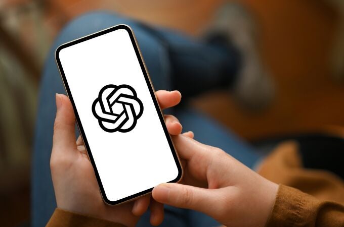 Unas manos sujetan un teléfono móvil con el logo de ChatGPT