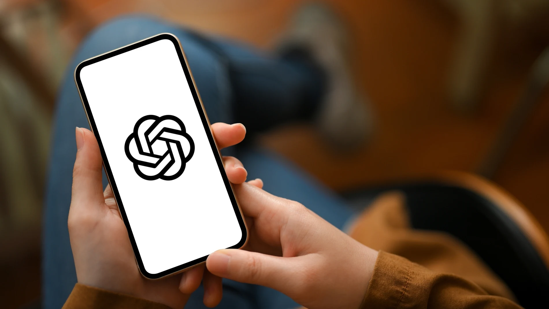 Unas manos sujetan un teléfono móvil con el logo de ChatGPT