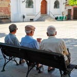 Tres hombres mayores sentados en la plaza de un pueblo