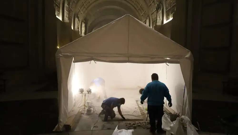 Los operarios trabajan sobre la tumba bajo la carpa instalada encima