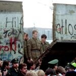 East German border guards look through a hole in the Berlin Wall after demonstrators pulled down the segment at Brandenburg Gate in Berlin, in this Nov. 11, 1989.