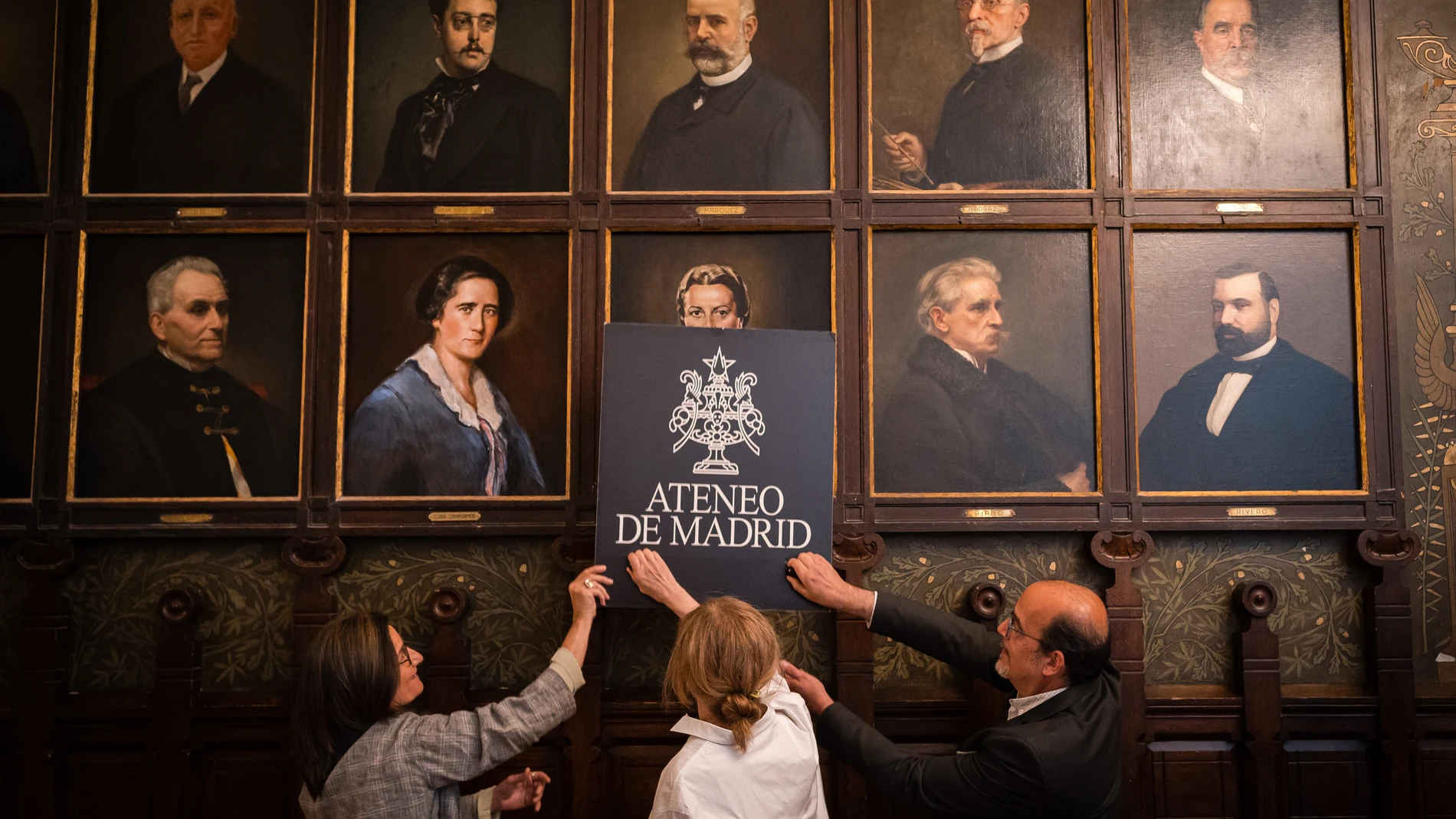 La abogada Inés de Alvear Trenor; la autora Carmen Mansilla y el presidente del Barrio de las Letras de Madrid, Enrique Garzo García, colocan el retrato de Elena Fortún, en la Galería de Ilustres del Ateneo, a 8 de mayo de 2023, en Madrid (España). El retrato de Elena Fortún ha subido a la Galería de Ilustres del Ateneo dentro del proyecto ‘Las mujeres en su sitio’. Esta acción nació con el objetivo de homenajear a la escritora, creadora de Celia y renovadora de la literatura infantil y juvenil del siglo XX y vecina del barrio. A partir de hoy, Elena Fortún ocupará su lugar junto a Carmen Laforet, Clara Campoamor, Almudena Grandes y Carmen de Burgos, para dar visibilidad a las mujeres ateneístas que formaron también parte de la historia del Ateneo pero que no tenían su retrato entre los 188 hombres ilustres de la Galería. 08 MAYO 2023;ELENA FORTÚN;CARMEN MANSILLA;GALERÍA DE ILUSTRES;ATENEO;RETRATO Diego Radamés / Europa Press 08/05/2023