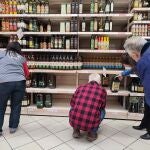 Varias personas compran aceite en un supermercado de Madrid, donde algunas estanterías permanecen vacías a causa de la huelga indefinida de transporte.