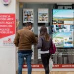  Una pareja se detiene a observar las propiedades en venta anunciadas en el escaparate de una agencia inmobiliaria de Menorca.