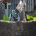 Un agente de la Policía Científica y un inspector recopilan pruebas en la infravivienda donde fue asesinada una mujer de 33 años en Pontevedra