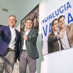 Juanma Moreno y José Luis Sanz, junto a un retrato del presidente andaluz con Feijóo