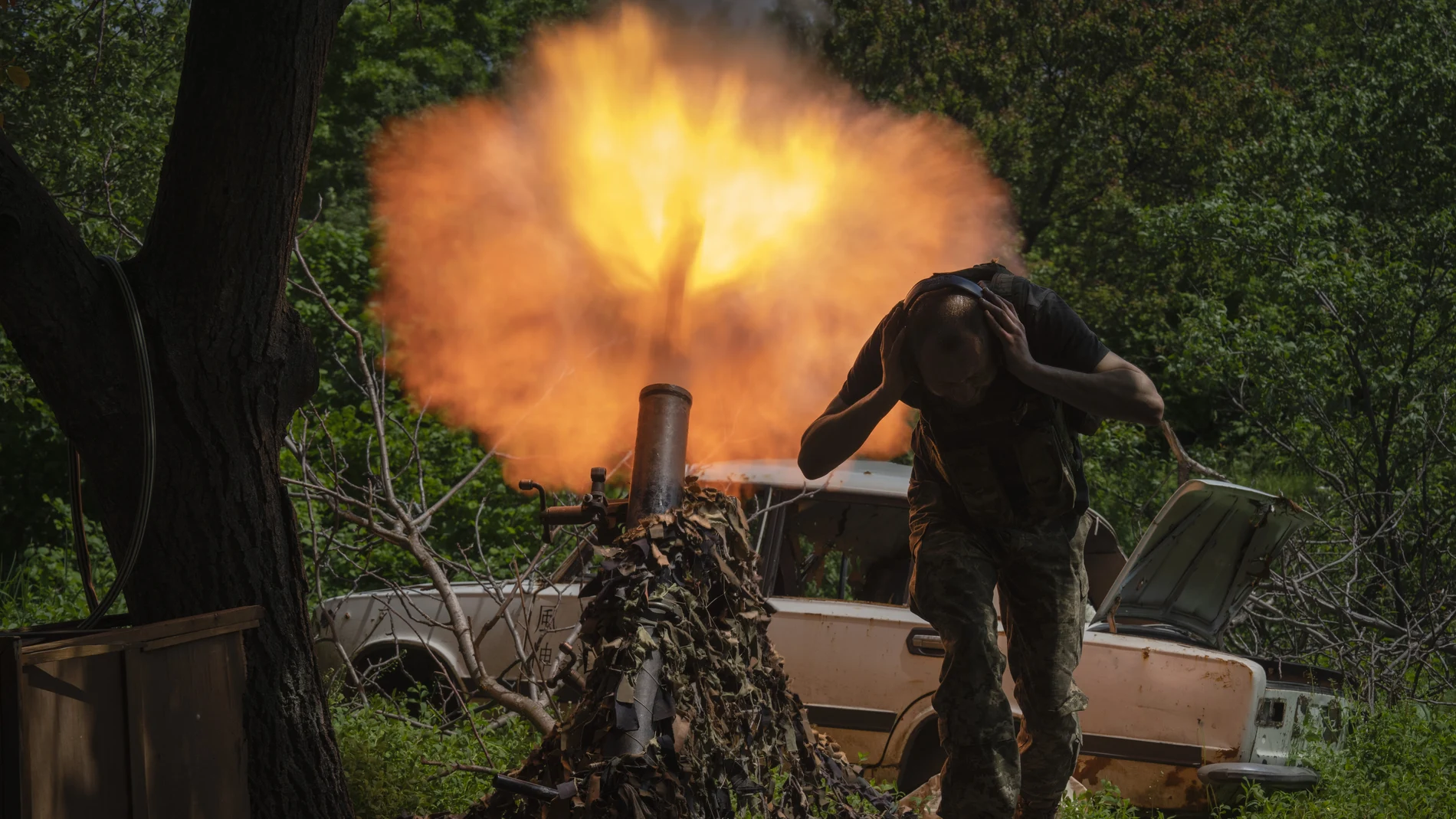 A Ukrainian soldier covers his ears while firing a mortar at Russian positions on the frontline near Bakhmut, Donetsk region, Ukraine, Monday, May 29, 2023.