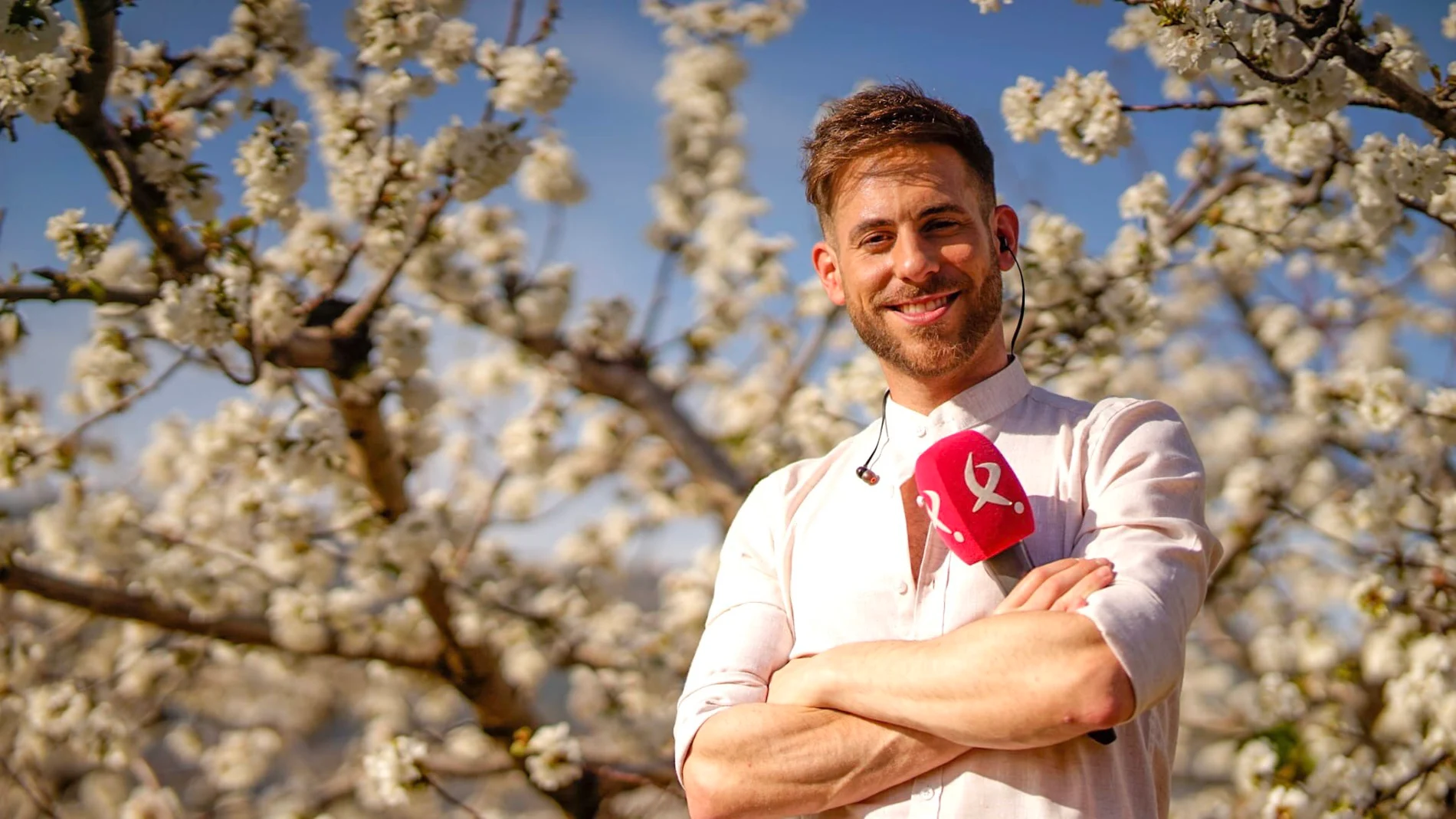 El presentador Cesar Muñoz delante de un almendro en flor en el Valle del Jerte