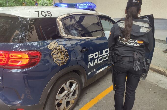 Imagen de archivo de una agente de la Policía Nacional junto al coche