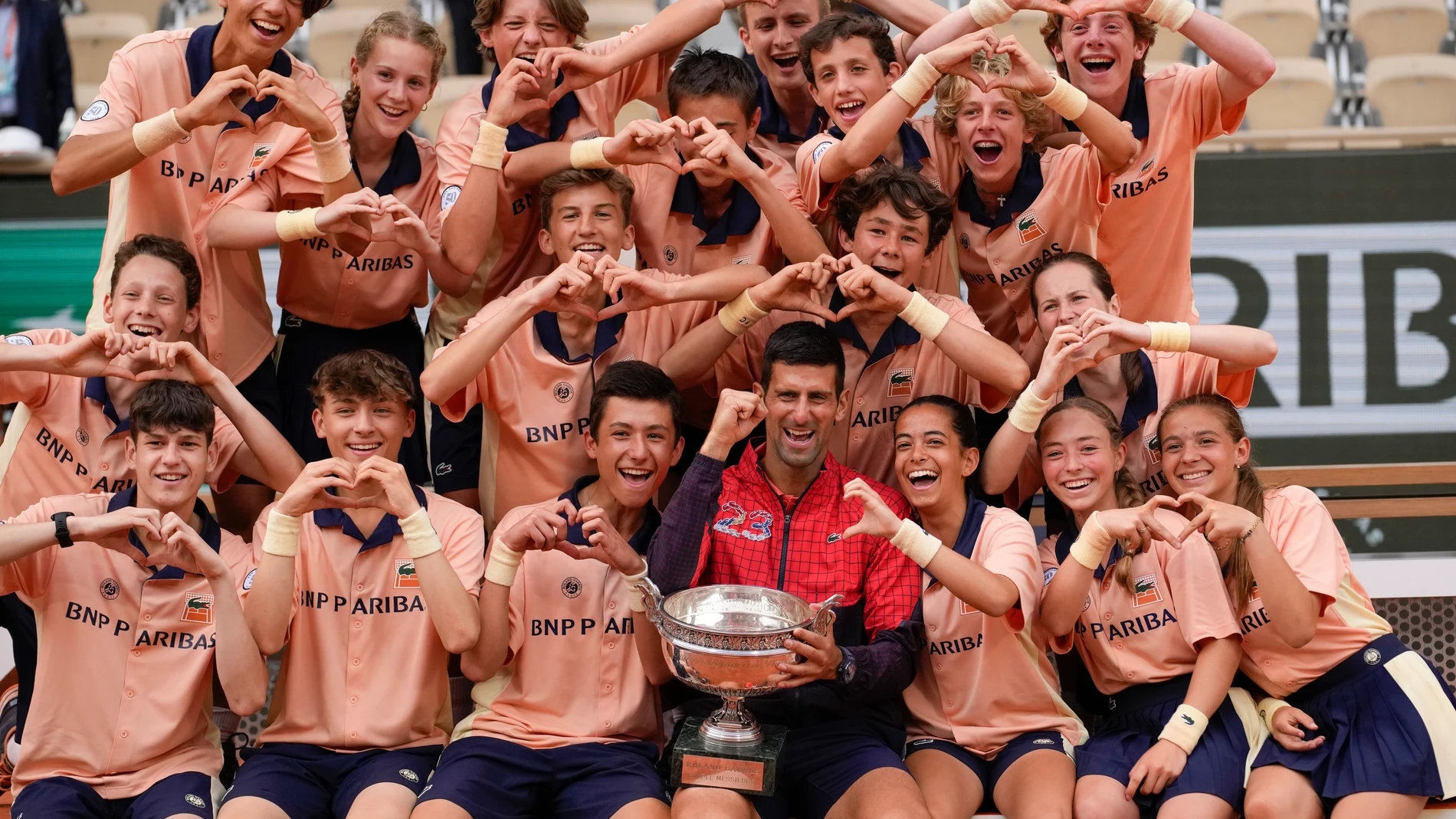 Serbia's Novak Djokovic poses with ball girls and boys as he celebrates winning the men's singles final match of the French Open tennis tournament against Norway's Casper Ruud in three sets, 7-6, (7-1), 6-3, 7-5, at the Roland Garros stadium in Paris, Sunday, June 11, 2023. Djokovic won his record 23rd Grand Slam singles title, breaking a tie with Rafael Nadal for the most by a man. (AP Photo/Christophe Ena)