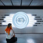 Una visitante delante del panel que explica los factores que hacen que creamos noticias falsas