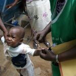 Health workers paint the finger Dele Okundayo after receiving polio vaccines in Lagos, Nigeria, Monday, Feb. 23, 2004. Nigerian health wokers kicked off a massive polio immunization campaign for 63 million children across West and central Africa to stop polio outbreak. The child's finger is painted to stop duplication of immunization.