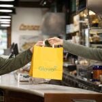 Repartidor de Glovo! haciendo la entrega de un pedido en una de sus bolsas de papel