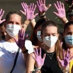 Varias mujeres con las manos pintadas guardan un minuto de silencio por las víctimas de la violencia machista