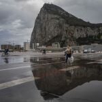 People cross the Gibraltar airport runway towards the border crossing with Spain, backdropped by the Gibraltar rock, in Gibraltar, Friday, March 5, 2021.