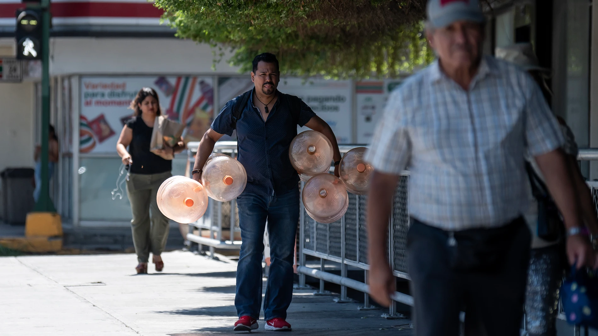 MEX8863. MONTERREY (MÉXICO), 28/06/2023.- Un hombre camina con garrafones de agua para su llenado debido a las altas temperaturas que se registran hoy, en la ciudad de Monterrey (México). La ola de calor que golpea a México ha ocasionado 36 muertes en el norteño estado de Nuevo León, informó este miércoles la Secretaría de Salud de la entidad. EFE/Miguel Sierra
