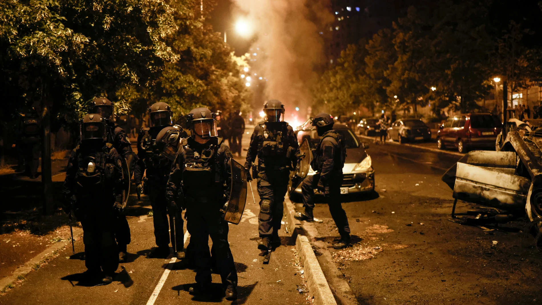 Nanterre (France), 29/06/2023.- Riot police walk near a burnt car during clashes with protesters in Nanterre, near Paris, France, 29 June 2023. Violence broke out after police fatally shot a 17-year-old during a traffic stop in Nanterre on 27 June 2023. According to the French interior minister, 31 people were arrested with 2,000 officers being deployed to prevent further violence. (Protestas, Disturbios, Francia) EFE/EPA/YOAN VALAT