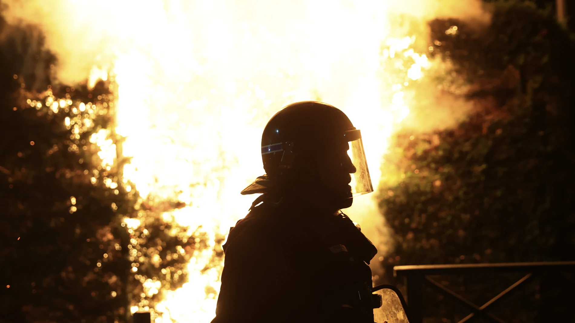 A riot police officer is silhouetted as he walks in front of a fire on the third night of protests sparked by the fatal police shooting of a 17-year-old driver in the Paris suburb of Nanterre, France, Thursday, June 29, 2023. The June 27 shooting of the teen, identified as Nahel, triggered urban violence and stirred up tensions between police and young people in housing projects and other neighborhoods.