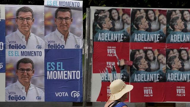 08/07/2023. Gijón (ASTURIAS).- Carteles electorales de PP y PSOE compartiendo valla esta mañana en las cercanías de la playa del Arbeyal.- EFE/Paco Paredes