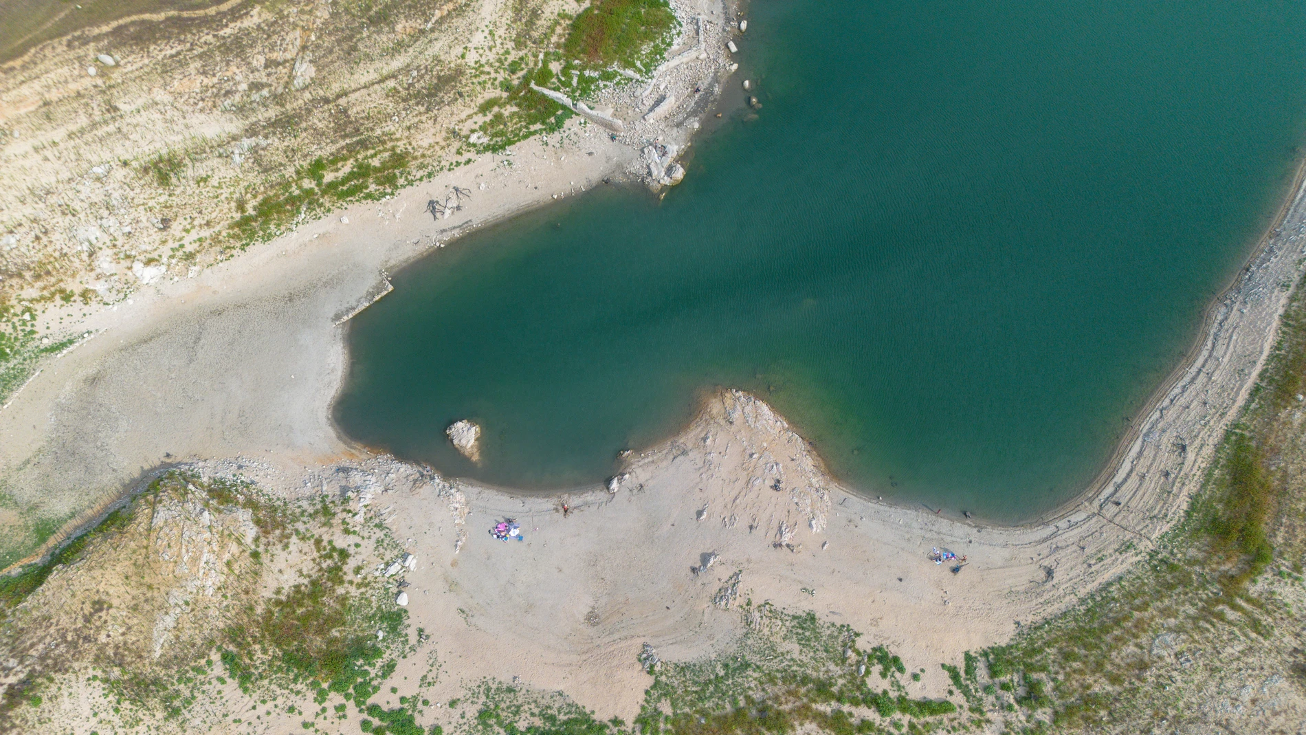 Vista aérea del pantano Darnius-Boadella, a 30 de julio de 2023, en Darnius, Girona, Cataluña (España). El pantano de Darnius-Boadella se encuentra solo al 20 % de su capacidad debido a la sequía de este mes. Un julio seco y caluroso ha provocado que las reservas en los embalses de Cataluña no alcancen el 28%. Por ello la parroquia de Darnius y el grupo de fe de adultos han organizado misa junto al embalse para reflexionar "sobre la sequía y el valor del agua". También han colaborado el arci...