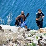 Un agente de la Guardia Civil con uno de los migrantes sirios que ha llegado a nado a las costas de Ceuta, en la barriada del Sarchal, a 31 de julio de 2023, en Ceuta (España). La Guardia Civil ha interceptado a dos migrantes sirios en una zona de rocas de la barriada del Sarchal de Ceuta. Los dos hombres venían equipados con trajes de neopreno y aletas y se prevé que hayan sido arrojados al mar a varias millas de la costa de Ceuta. Los agentes les han intervenido pasaportes sirios y los han trasladado a dependencias policiales en la frontera del Tarajal para la identificación y los trámites de filiación. 31 JULIO 2023;CEUTA;MIGRANTES;SIRIOS Antonio Sempere / Europa Press 31/07/2023
