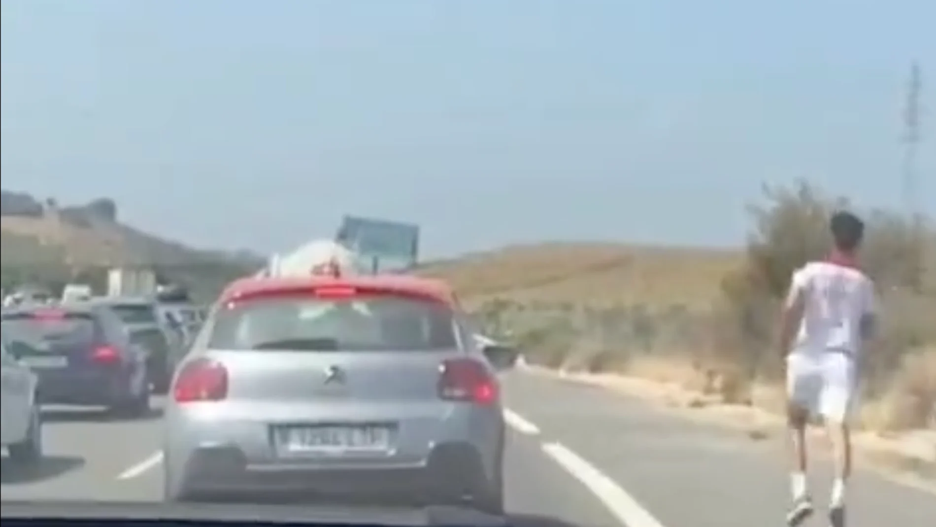 Joven corriendo a lo largo de la autopista en medio de un atasco
