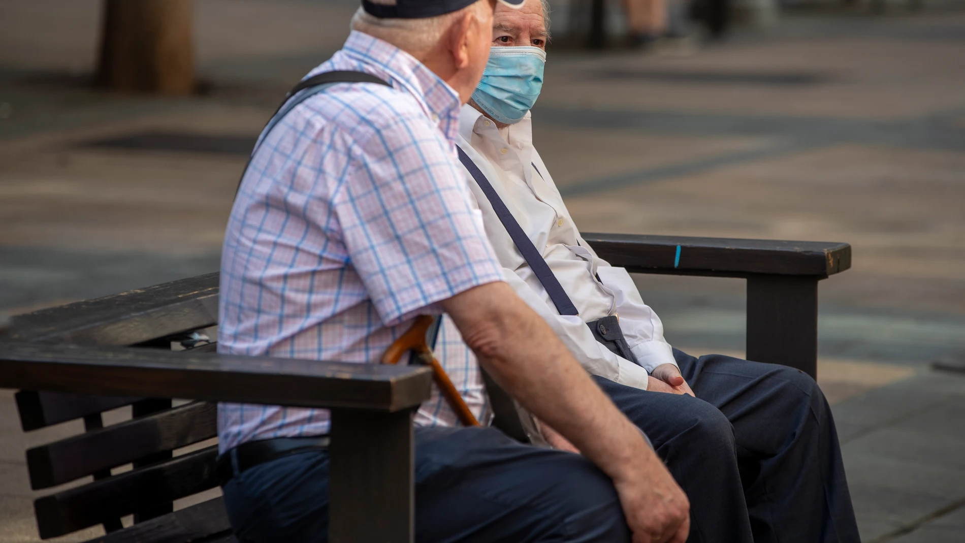 VITORIA, 09/08/2023.- Dos hombres, uno protegido con mascarilla, charlan sentados en un banco este miércoles en Vitoria. La venta de test de antígenos para la detección del covid-19 se ha duplicó en la última semana de julio respecto al mismo período del mes anterior, sobre todo en Navarra y el País Vasco. EFE/David Aguilar