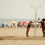 Dos mujeres se refrescan en una ducha en la playa