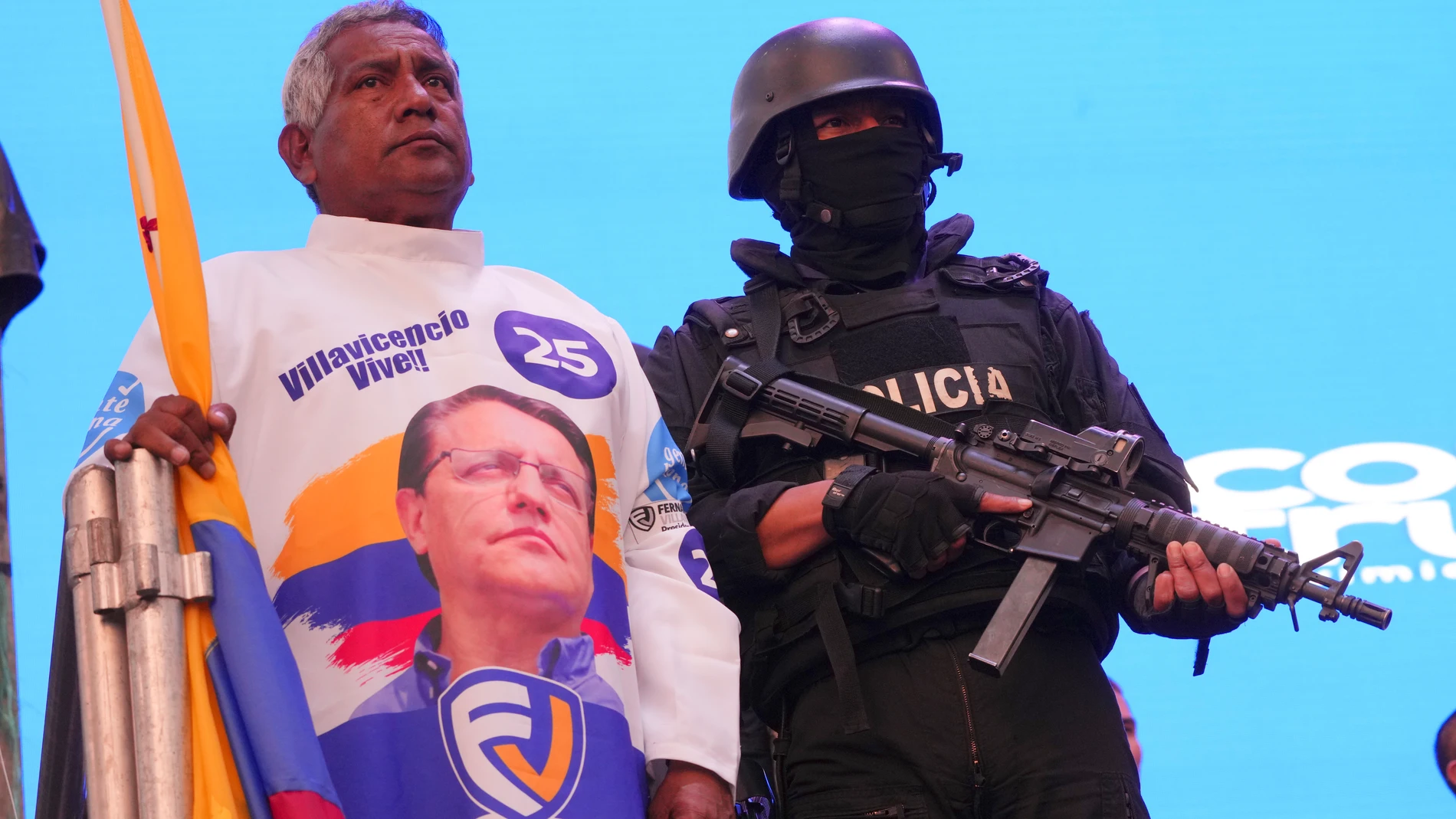 A supporter of the "Movement Construye" party wearing a shirt with the image of slain candidate Fernando Villavicencio, stands next to a police officer in tactical gear during a Catholic Mass prior to their closing campaign rally in Quito, Ecuador, Thursday, Aug. 17, 2023. The upcoming snap election set for Aug. 20 was called after President Guillermo Lasso dissolved the National Assembly by decree in May, to avoid being impeached. (AP Photo/Dolores Ochoa)