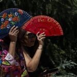 Dos mujeres se protegen del sol con abanicos. EFE/Chema Moya