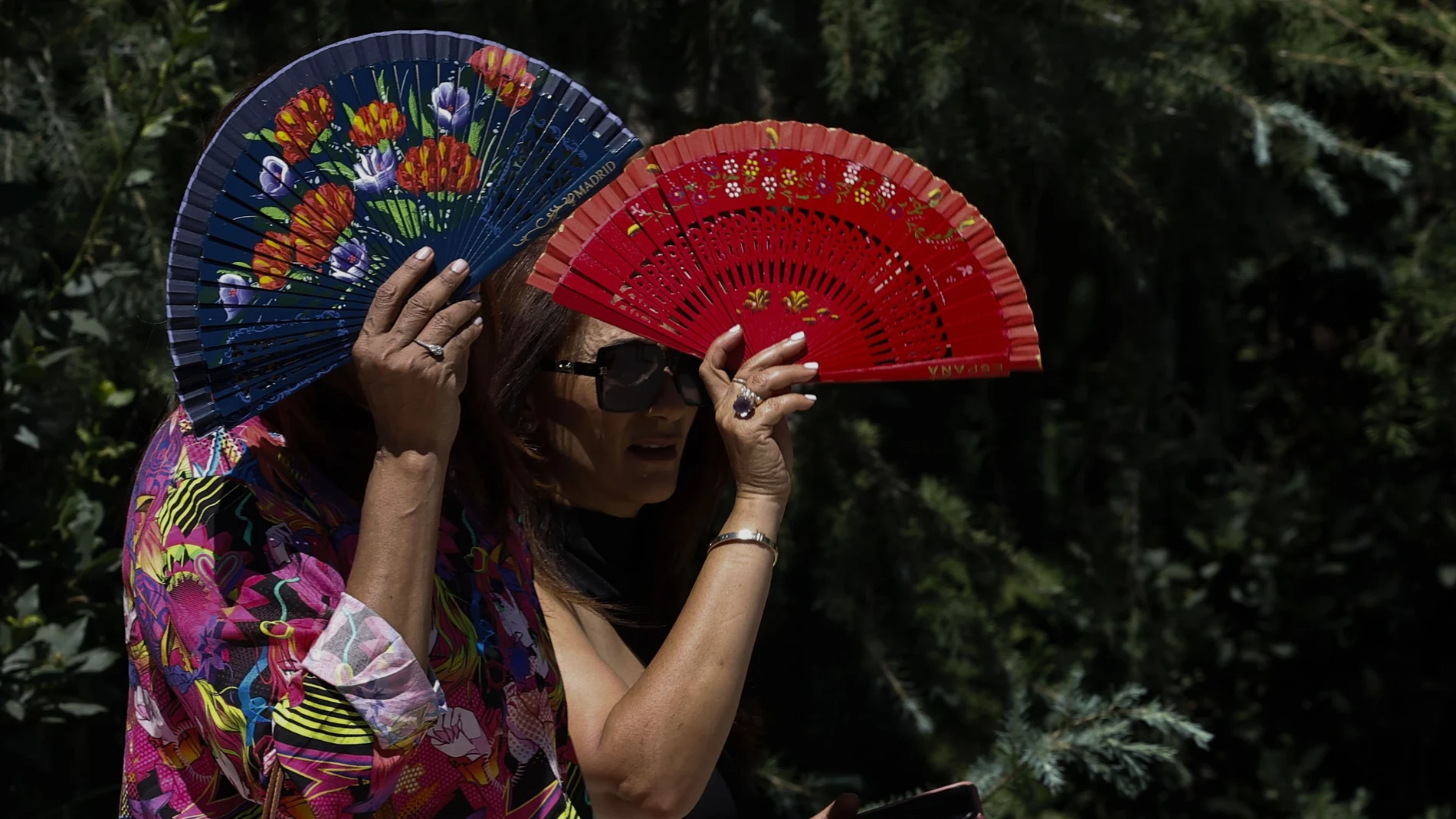 Dos mujeres se protegen del sol con abanicos. EFE/Chema Moya
