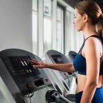 Un mujer entrena en una cinta de correr en un gimnasio