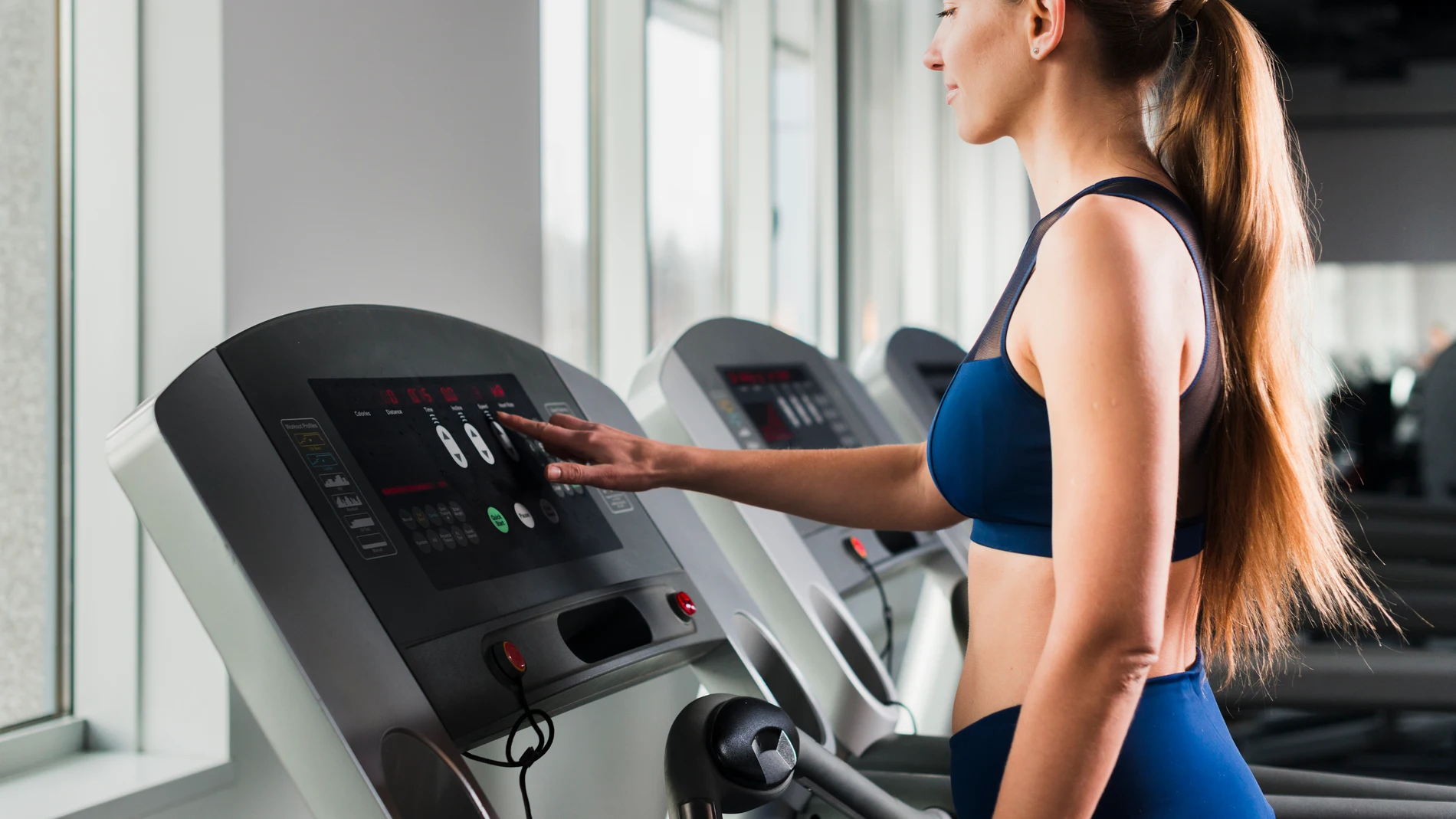 Un mujer entrena en una cinta de correr en un gimnasio