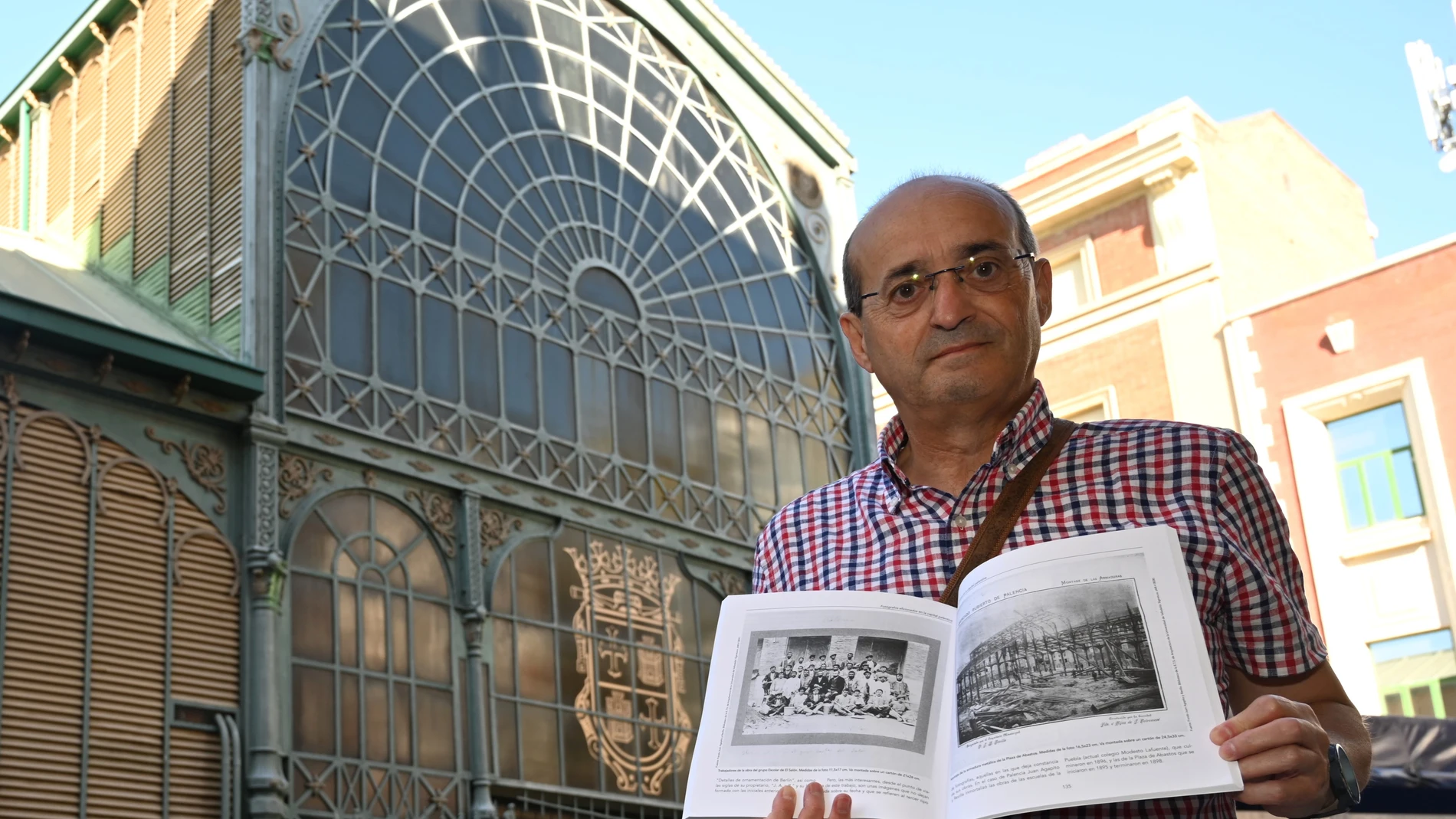 PALENCIA, 24/'8/2023.- Javier de la Cruz Macho, doctor y catedrático en Historia, posa con su libro "Capturar la luz" en la Plaza de Abastos de Palencia uno de los lugares fotografiados durante su construcción en 1898. EFE/Almudena Álvarez