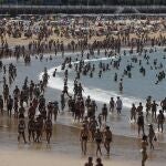 Donostiarras y visitantes disfrutan de un día soleado en la playa de la Concha de San Sebastián.