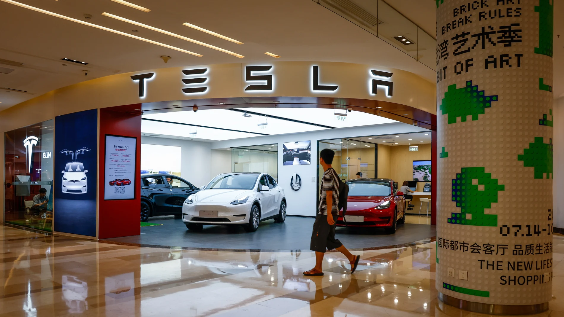 A man walks next to a Tesla showroom in Beijing, China.