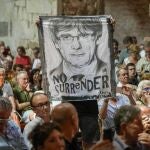 CODALET, (FRANCIA), 21/08/2023.-Un asistente sostiene una pancarta con la cara de Carles Puigdemont y la frase "No Surrender" este lunes en la abadía de Sant Miquel de Cuixà, en Codalet (Francia), durante el acto homenaje al músico Pau Casals con motivo de los 50 años de su muerte, al que el expresidente de la Generalitat también ha asistido. EFE/David Borrat