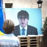 Un niño observa la intervención telemática de Puigdemont en el mitin central del partido JxCAT, en Amer, Girona.