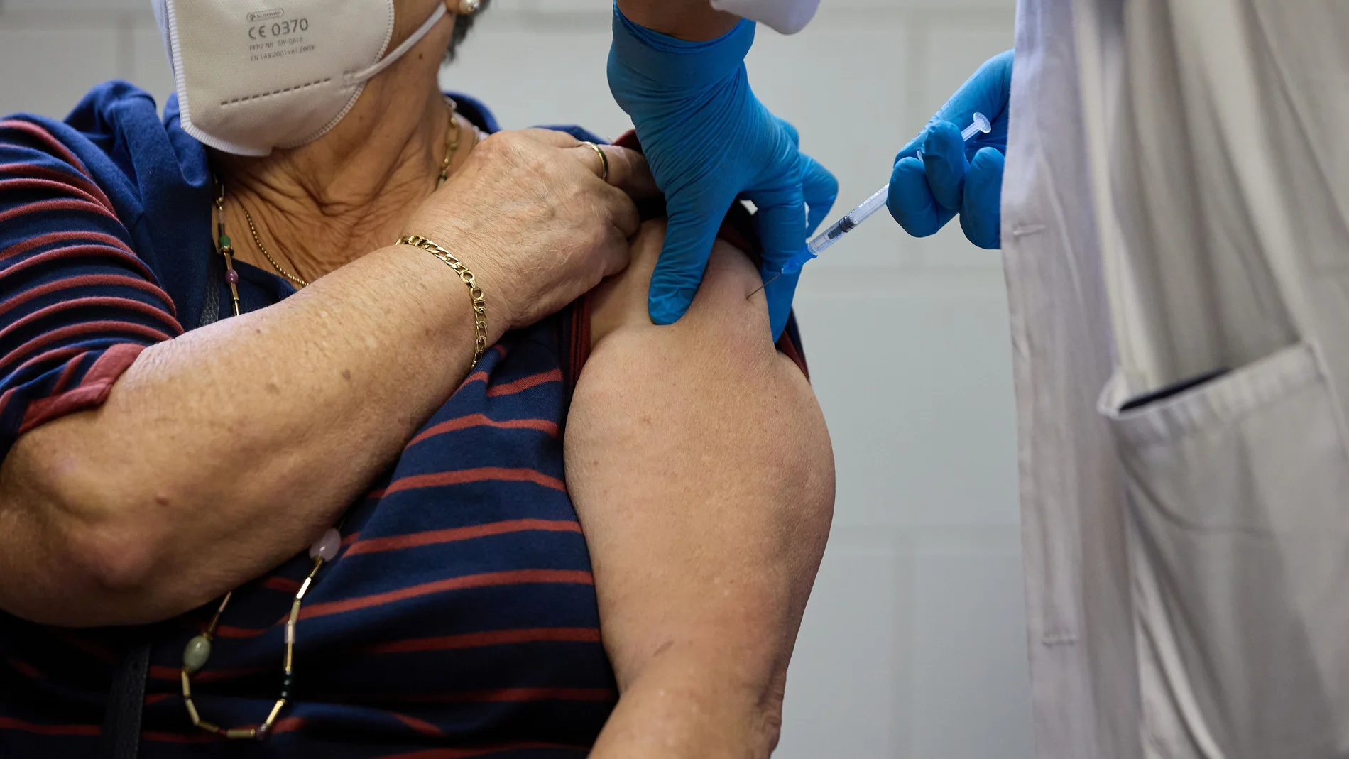 Un sanitario vacuna a una mujer mayor