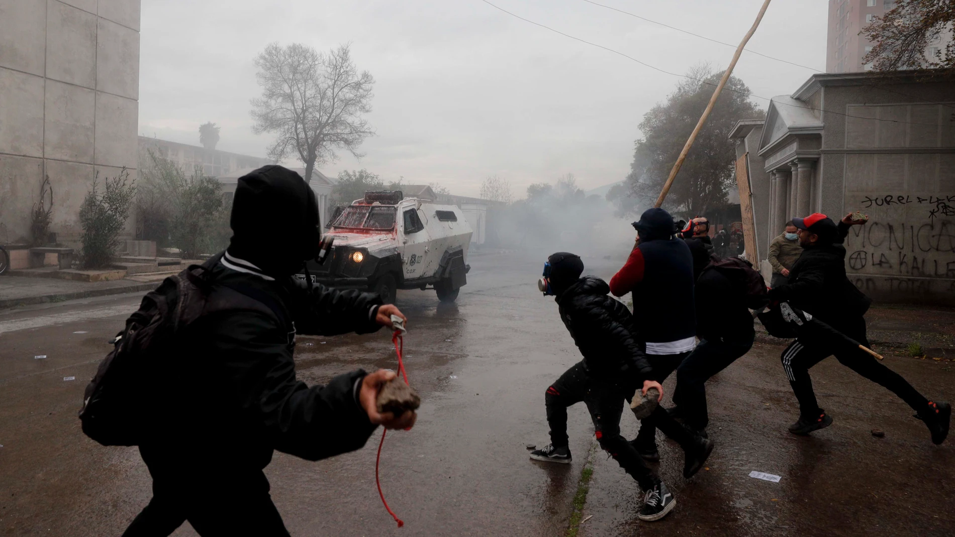 Protesters clash with police during a march marking the 50th anniversary of the 1973 military coup led by Gen. Augusto Pinochet, at the cemetery in Santiago, Chile, Sunday, Sept. 10, 2023. (AP Photo/Luis Hidalgo)
