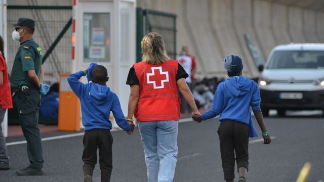 Una voluntaria de la Cruz Roja acompaña a dos menores migrantes en Canarias