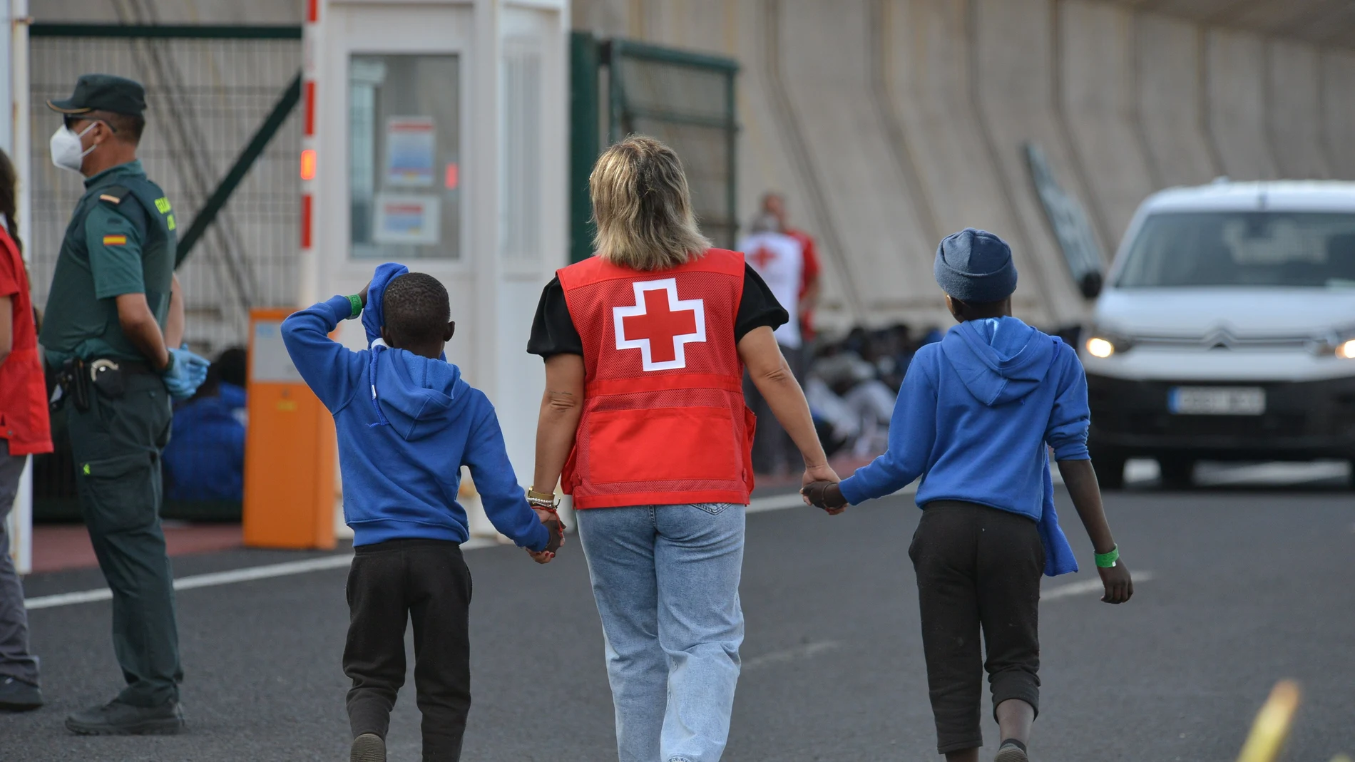 Una voluntaria de la Cruz Roja acompaña a dos menores migrantes en Canarias