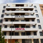 Edificio de viviendas con un enorme cartel con la palabra venta.
