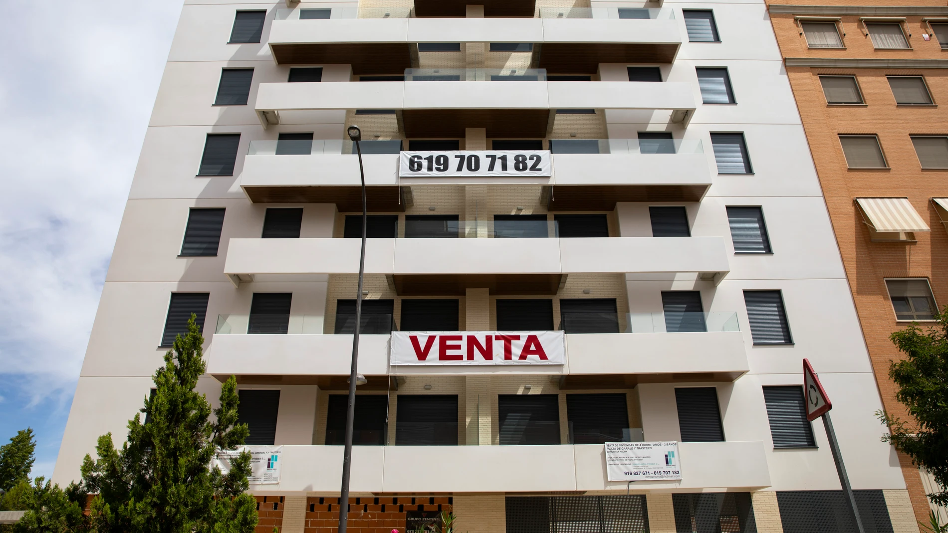 Edificio de viviendas con un enorme cartel con la palabra venta
