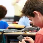 Niño con teléfono móvil en el colegio.