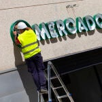 Dos operarios colocan el cartel luminoso de Mercadona en la fachada de una tienda. © Jesús G. Feria.